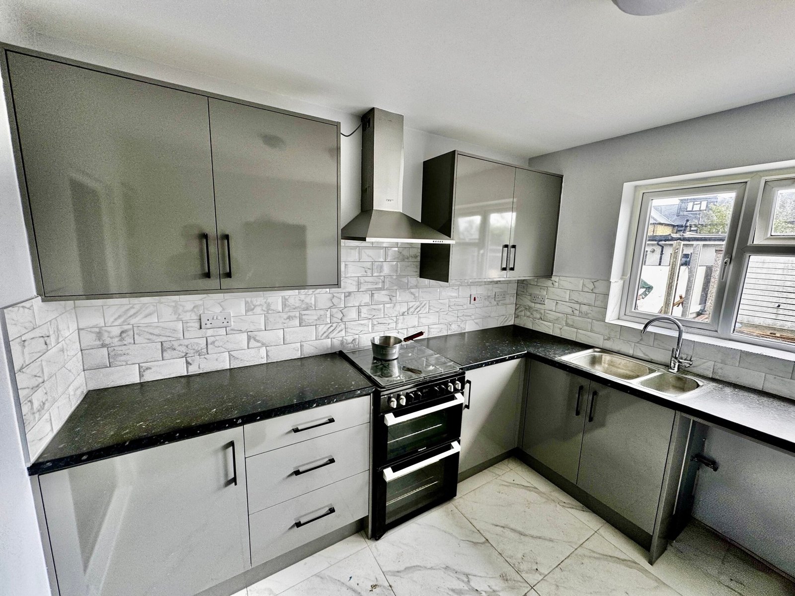 Modern grey kitchen renovation with marble tiles and black worktops in Uxbridge, London by Signature Build Properties
