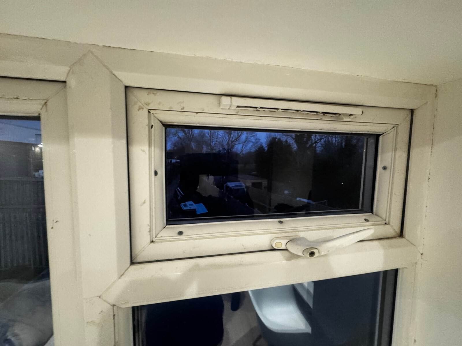 Window head in a Greenford home showing black mould, a grimy trickle vent and gaps in the sealant around the frame