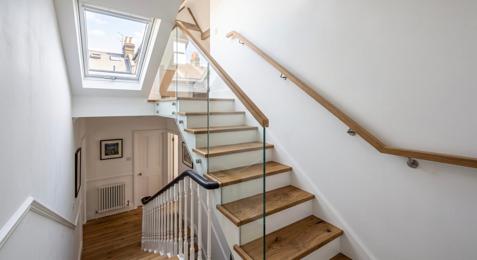 A finished loft conversion bedroom in a London terraced house with the bed under the ridge, eaves storage and rooflights, gained without losing a bedroom below